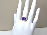 une image représentant la main d'un mannequin blanc portant une bague violette