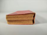 an old red book sitting on top of a white table