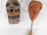 two wooden masks on a white surface with a rope