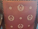 a chair that has a red seat with gold decorations on it