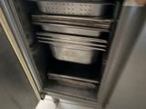 stainless steel oven with pans inside of it on a tiled floor