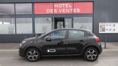 La petite voiture est garée devant l'hôtel, devant le bâtiment.