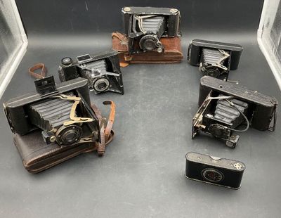 Plusieurs anciens appareils photo sont disposés en cercle sur une table