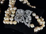 a close up of a necklace with pearls and a broocher