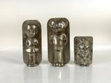 three silver metal figurines of a man and a woman