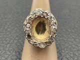 a close up of a ring with a yellow stone in it