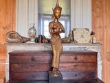 une statue représentant une personne assise sur une table en bois