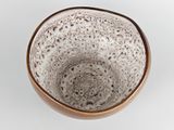 a brown and white bowl sitting on a white surface