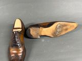 pair of men ' s brown leather shoes on a grey surface