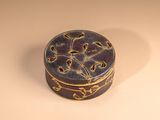 a small round box with a decorative design on it