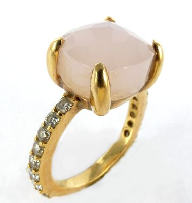 un gros plan d'une bague ornée d'une pierre rose entourée de diamants