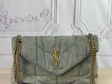 a small grey bag with a gold chain on a wooden table