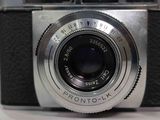 a silver camera with a black lens on a white table