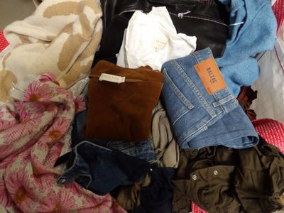 a pile of clothes that is sitting on a bed