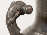 a silver vase with a dragon handle on a table