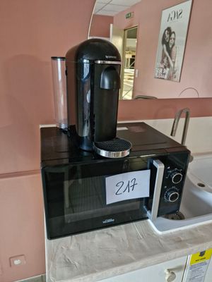 une cafetière posée sur un micro-ondes, sur un plan de travail