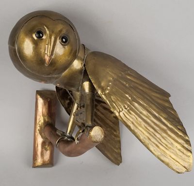 a gold owl sculpture on a wall mounted on a white wall