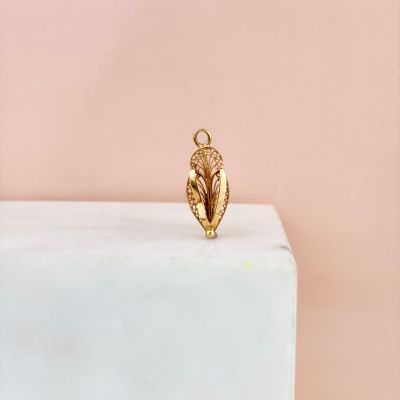 le pendentif en feuille d'or repose sur un bloc de marbre