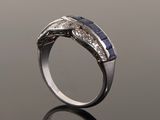 a close up of a diamond and sapphire ring on a reflective surface