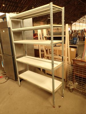 une étagère métallique avec des tablettes et un réfrigérateur dans une pièce