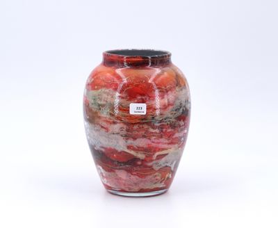 un vase rouge avec un couvercle noir posé sur une surface blanche