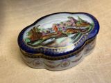 a blue and white box with a painting on it on a table