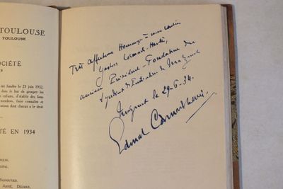 un livre ouvert, dont une page est couverte d'une écriture manuscrite, posé sur une table