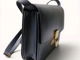 a black leather bag with a gold buckle on the front