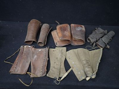 Plusieurs paires de vieilles bottes en cuir sont alignées sur une surface noire