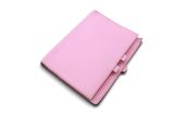 un carnet en cuir rose sur lequel repose un stylo, posé sur une surface blanche
