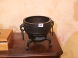 un pot noir posé sur une table, à côté d'une bougie bleue