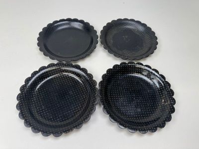 quatre assiettes en plastique noir posées sur une table blanche, sur fond blanc
