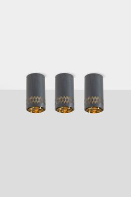 three black and gold lamps on a white surface