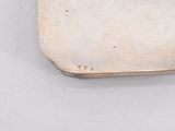 a silver purse with a handle on a white surface