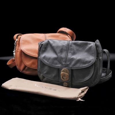 leather handbags are lined up on a black surface with a pouch