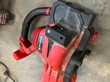 a red and black drill and some tools on the floor