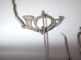 a silver necklace with a bird on it next to a pair of scissors