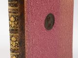 un vieux livre posé sur une table blanche, à côté d'un bouton