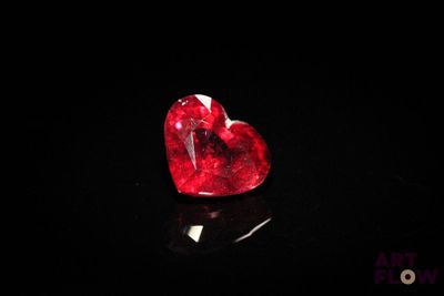 a close up of a red heart shaped diamond on a black surface