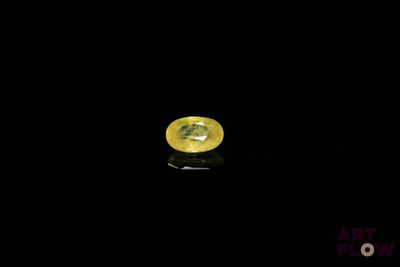 a close up of a yellow sapphire on a black surface