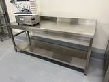 une table en acier inoxydable avec une cuisinière dans un coin
