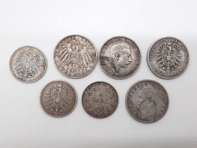 six types différents de pièces d'argent sur une surface blanche