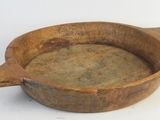 a wooden bowl with a handle on a white surface