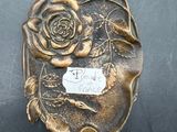 a metal object with a rose on it sitting on a table