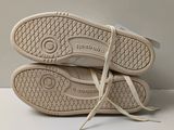 pair of white tennis shoes sitting on top of each other on a white surface