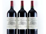 three bottles of red wine sitting next to each other on a white surface