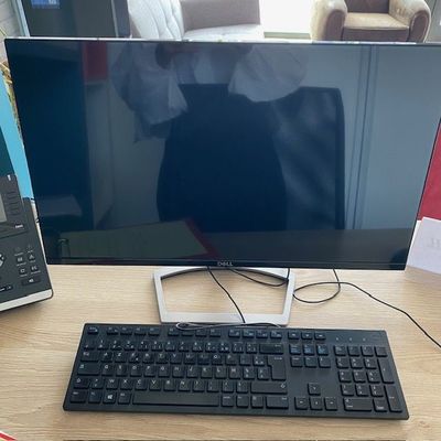 un écran d'ordinateur et un clavier posés sur un bureau, à côté d'un ordinateur portable