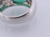 a ring with a green stone in it on a white surface