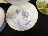 three plates with birds painted on them sitting on a table