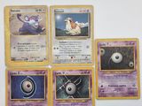 Plusieurs cartes Pokémon sont posées sur une surface blanche, sur fond blanc.